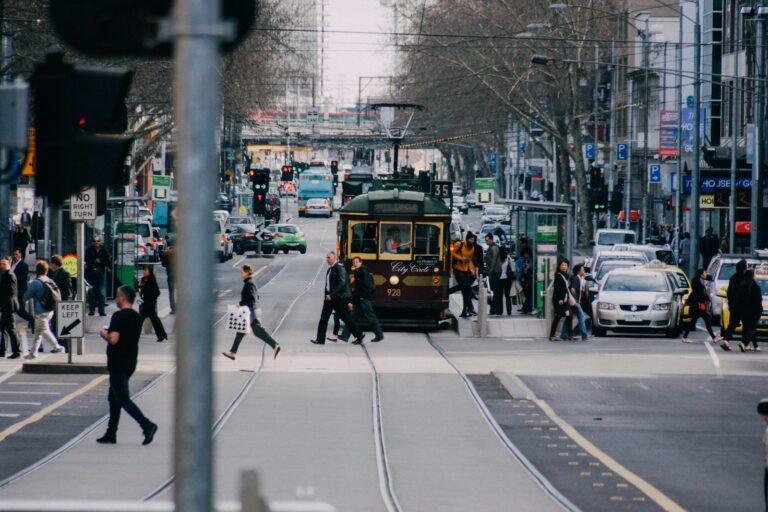 people crossing road near yellow train