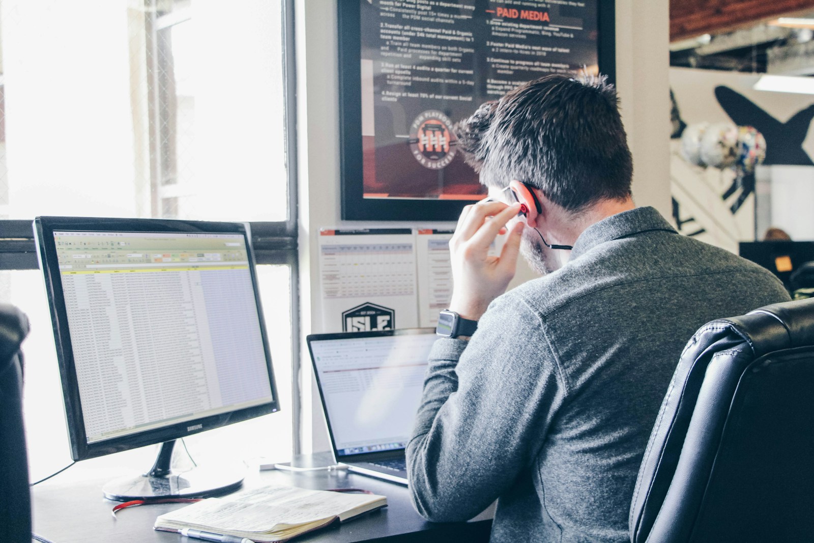 man in blue long-sleeved shirt sitting at table using laptop listening to IELTS Listening