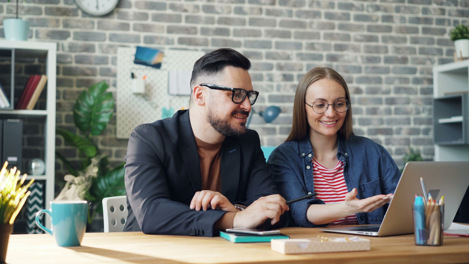 a man and a woman sitting at a table looking at a laptop