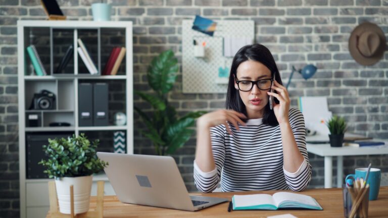 a woman sitting at a desk talking on a cell phone