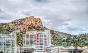 white and red concrete building near mountain under cloudy sky during daytime